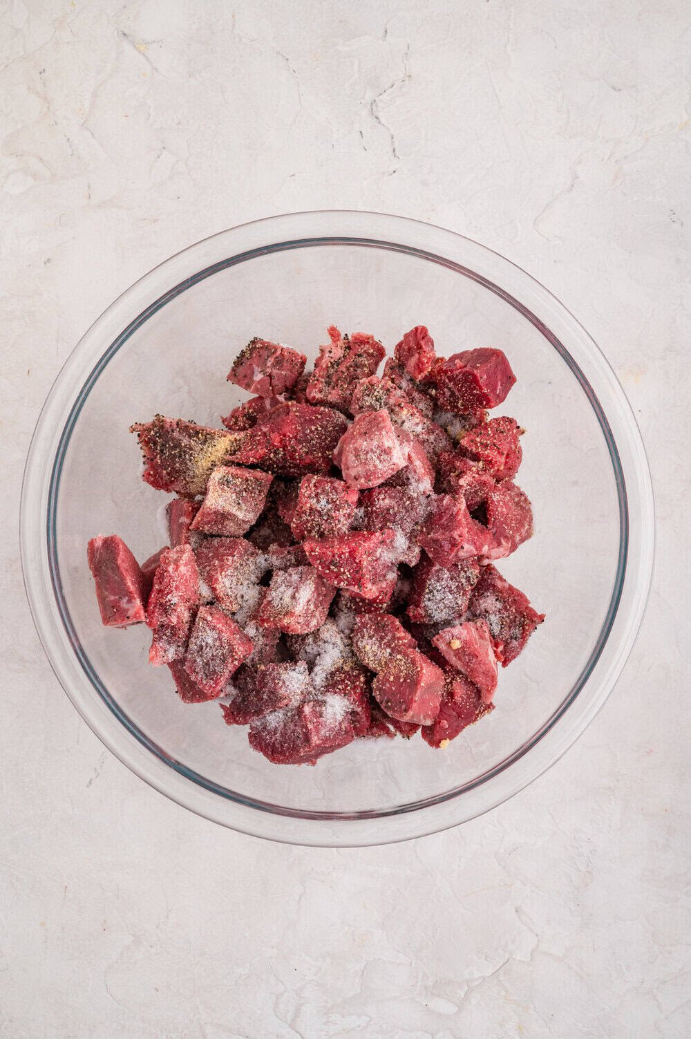 steak cubes and seasonings in clear glass bowl
