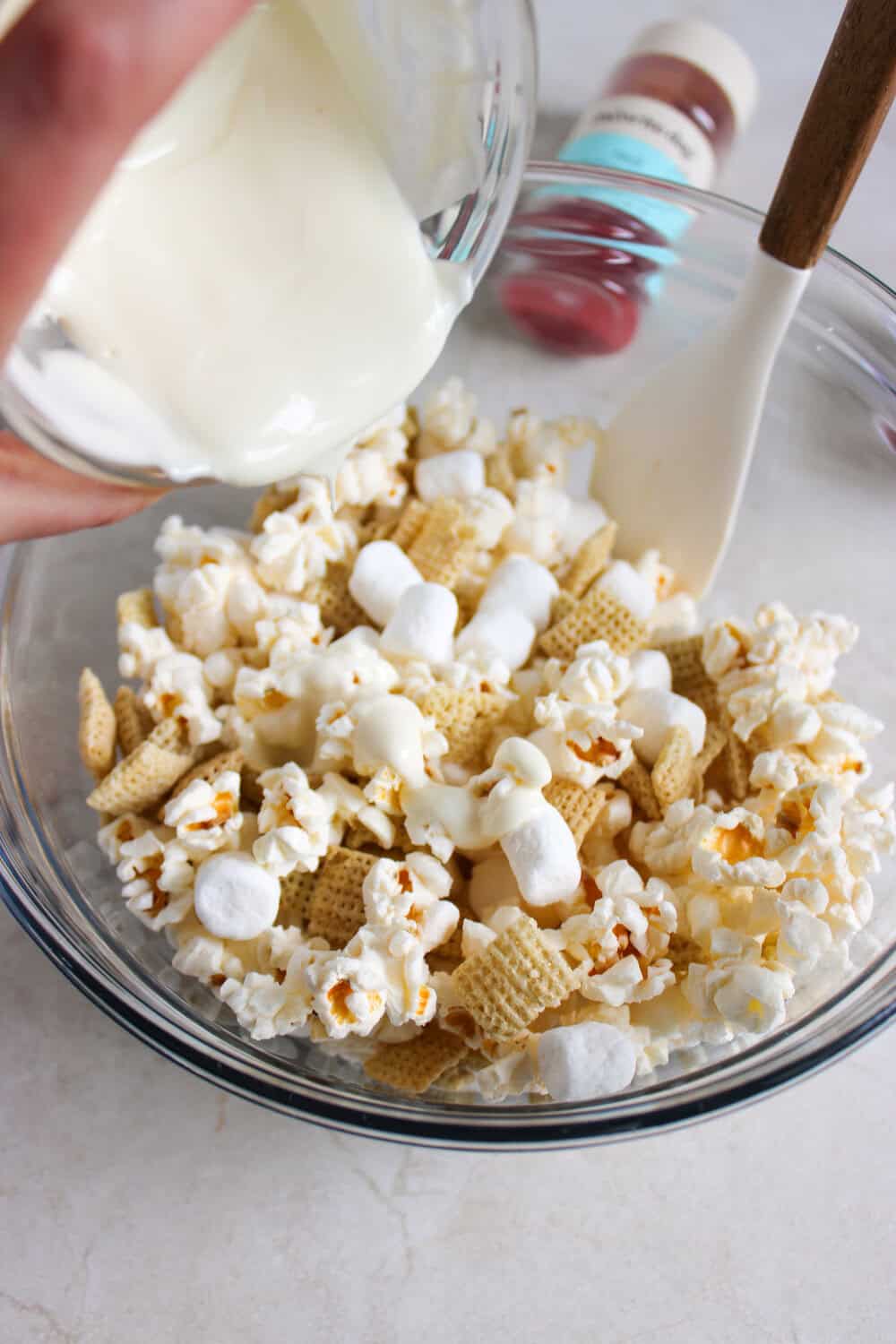 pouring white candy melts over popcorn