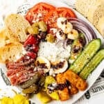 Savory Mediterranean salad with fresh vegetables, olives, boiled eggs, and toasted bread slices in a white bowl, garnished with spices and crumbled cheese for a flavorful meal.
