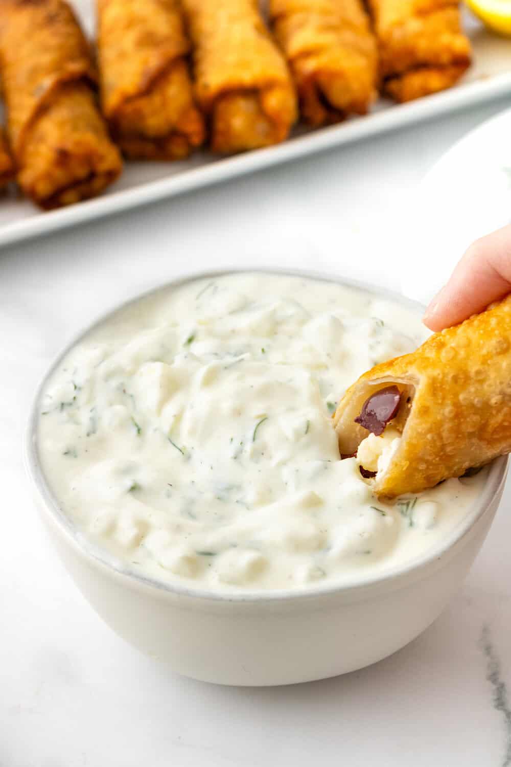 greek egg roll being dipped into Tzatziki sauce