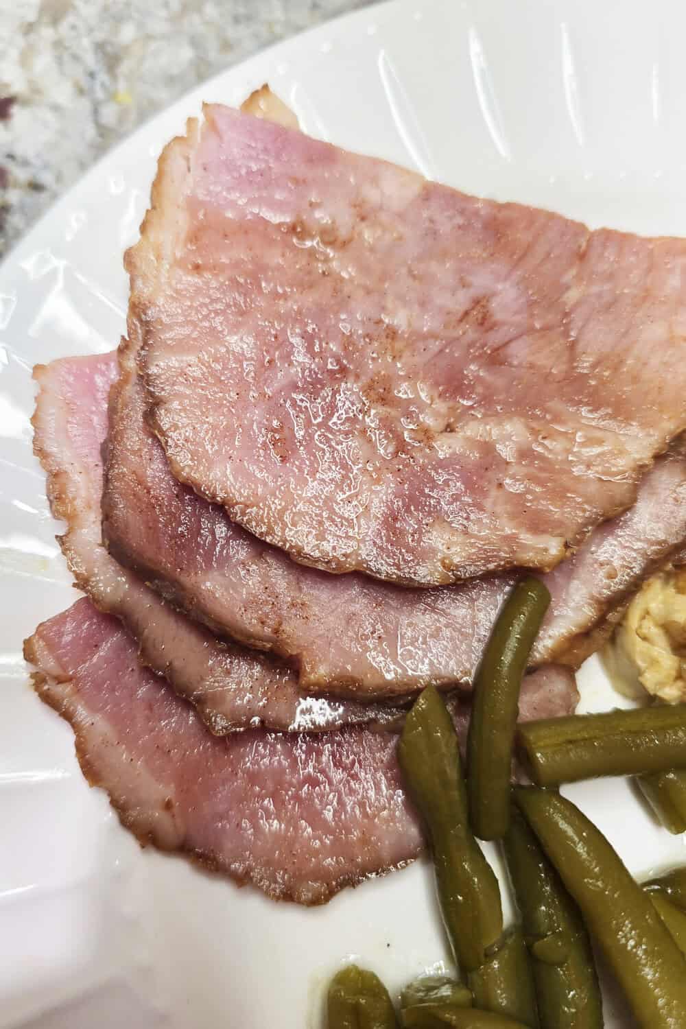 sliced ham on a plate with beans