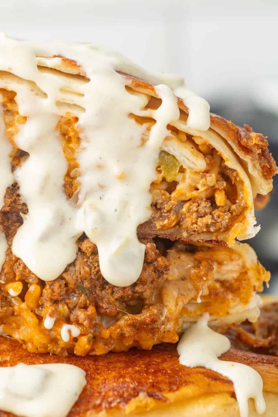 grilled cheese burrito cut in half and stacked with queso dripping off the top