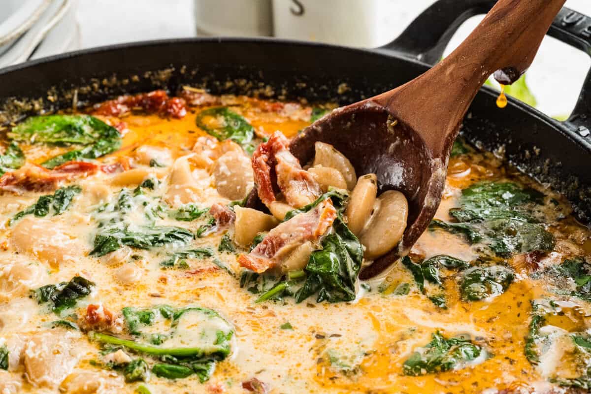 marry me butter beans in a skillet with a wooden spoon