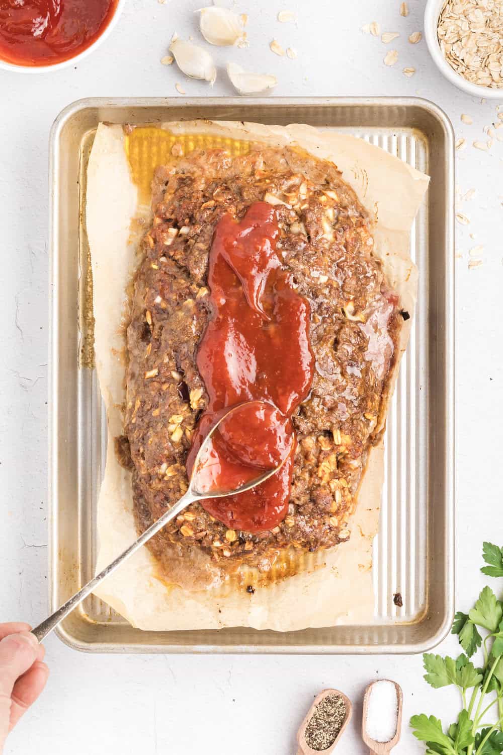 adding sauce to cooked meatloaf with oatmeal