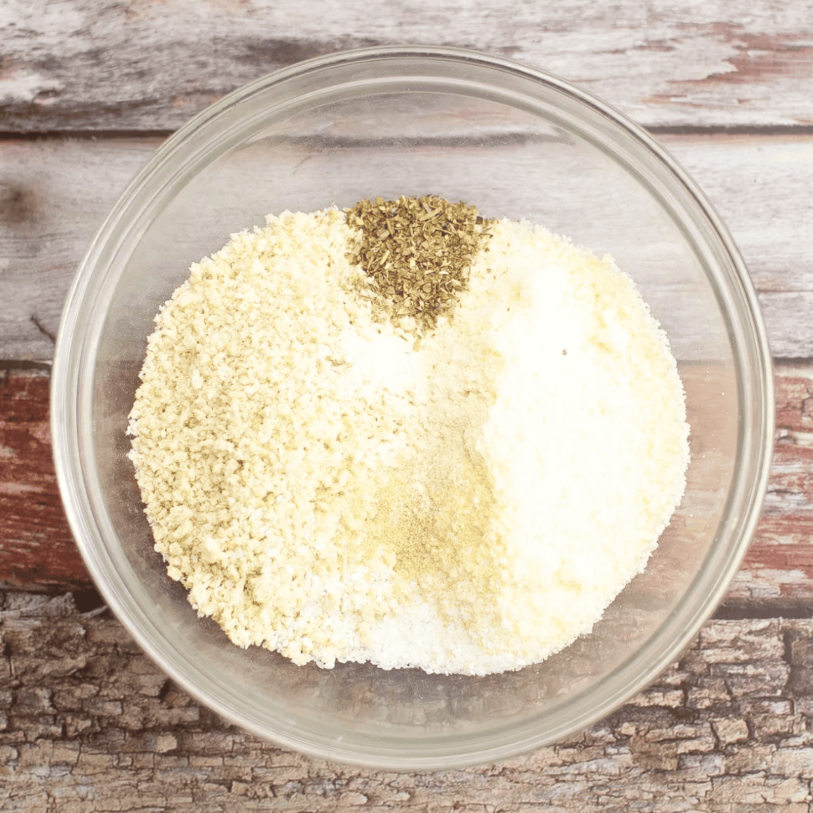 crumbs, Parmesan, one clove of crushed garlic, one teaspoon of onion powder, one teaspoon of salt, and one teaspoon of Italian Seasoning in a small mixing bowl