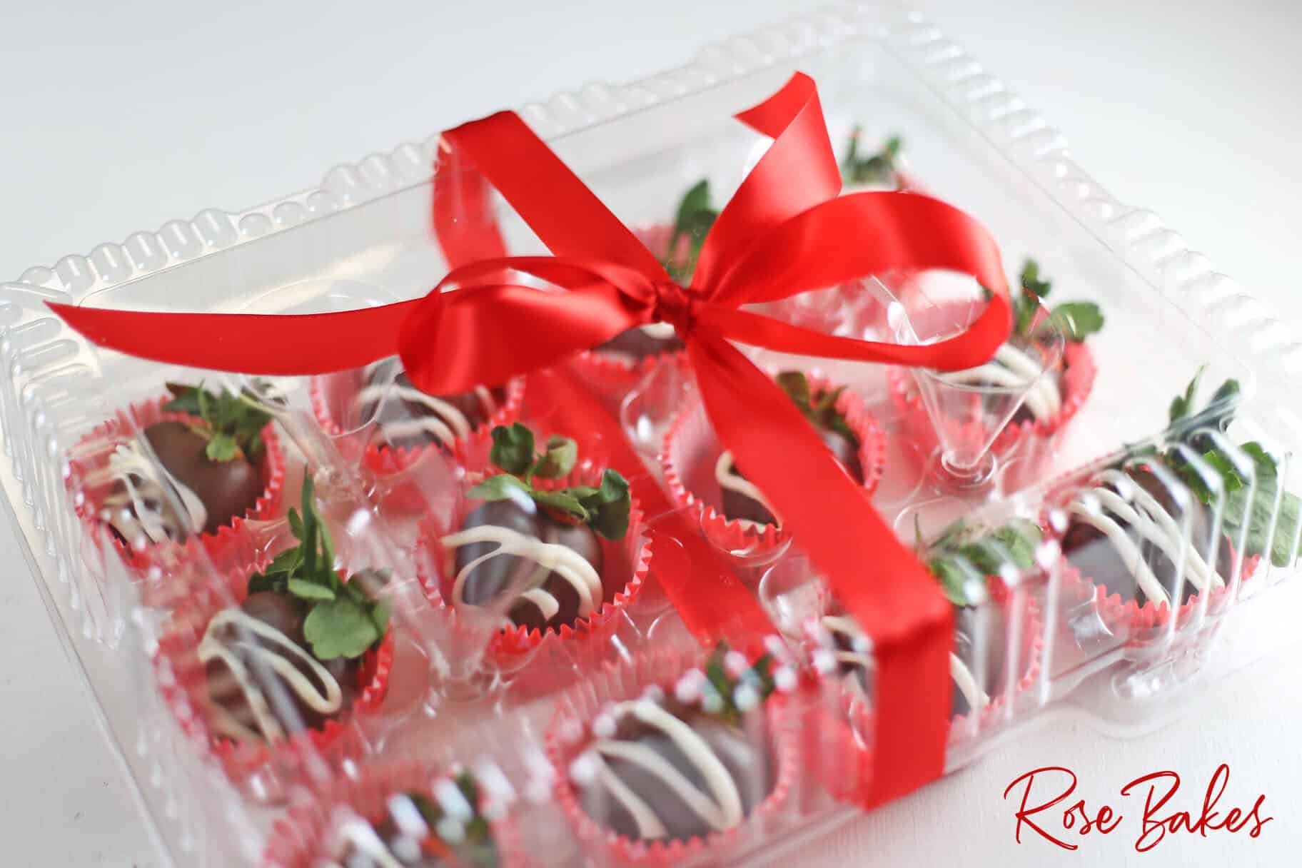 Chocolate Covered Strawberries with white drizzle in a clear box with a red ribbon