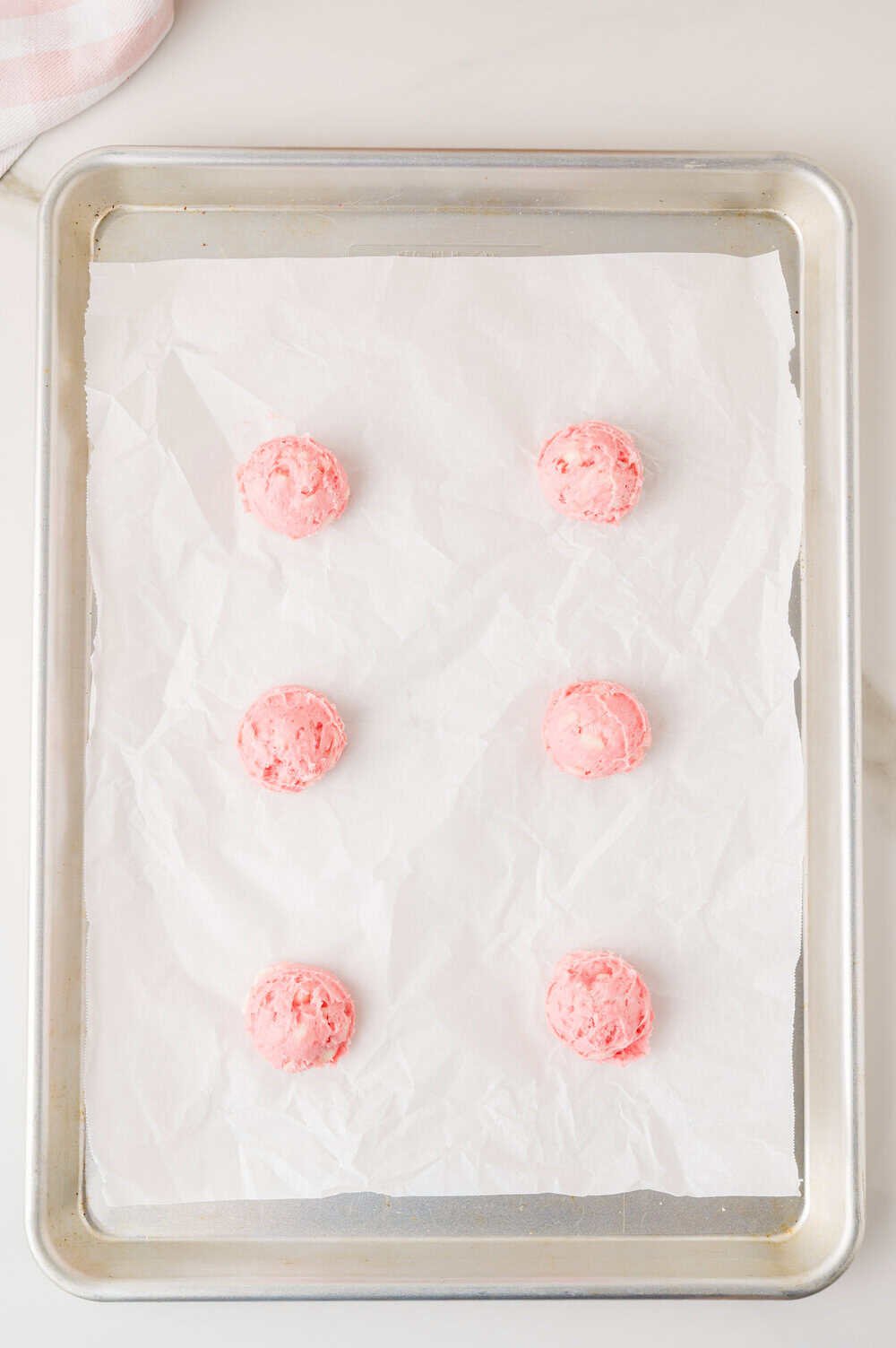balls of cookie dough on a baking sheet lined with parchment paper