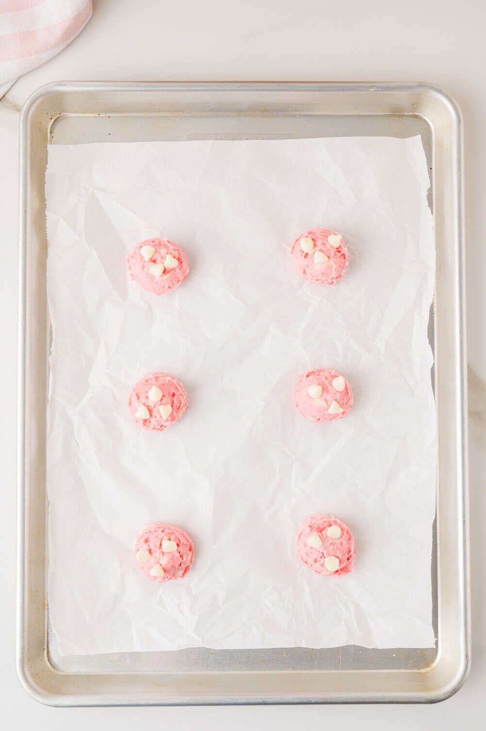 balls of cookie dough on a baking sheet lined with parchment paper  - extra chips pressed into the top