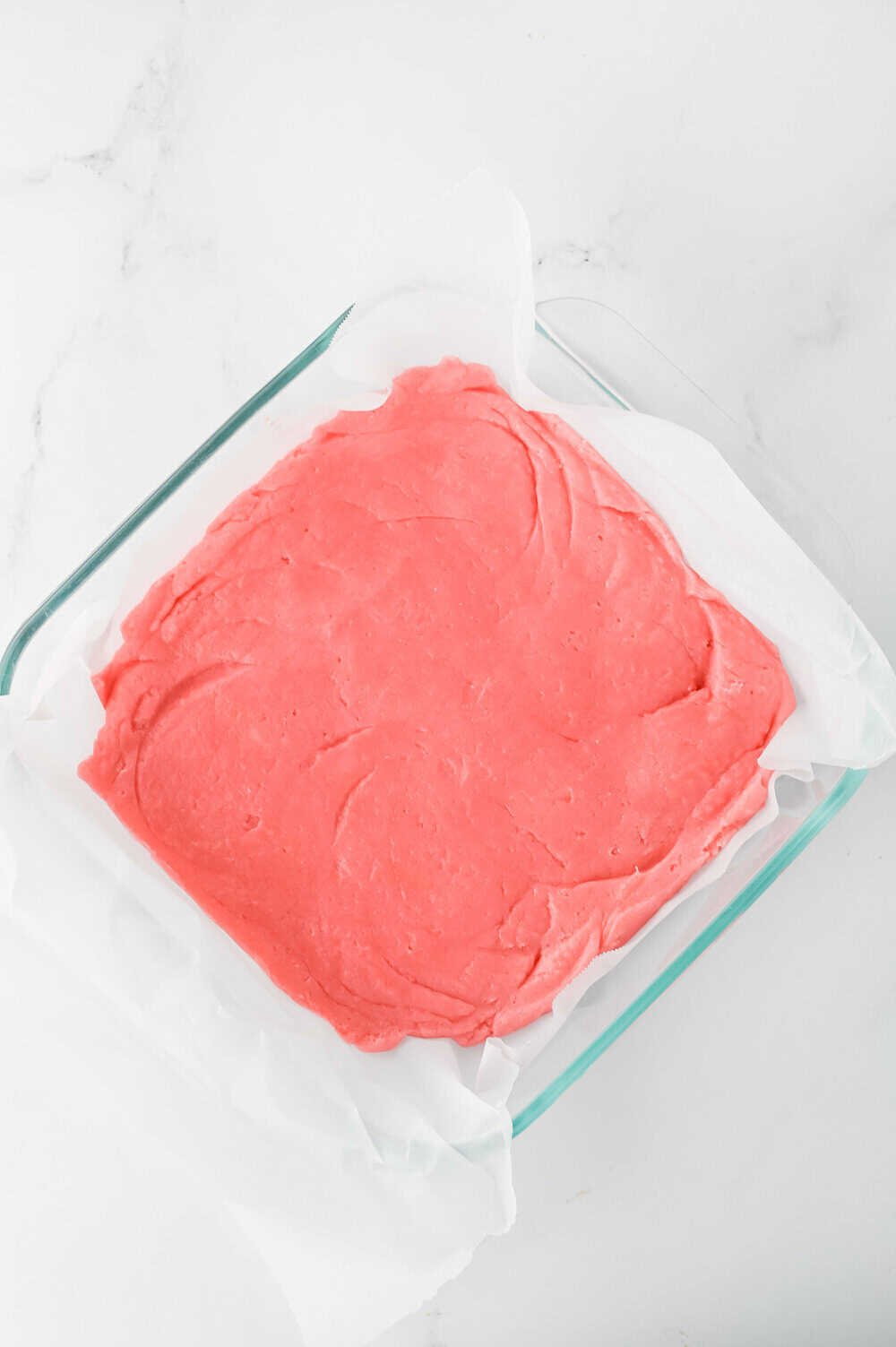 strawberry blondies batter pressed into parchment lined square pan