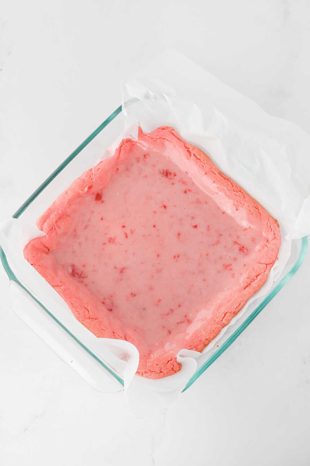 strawberry glaze poured over baked strawberry brownies in a square pan