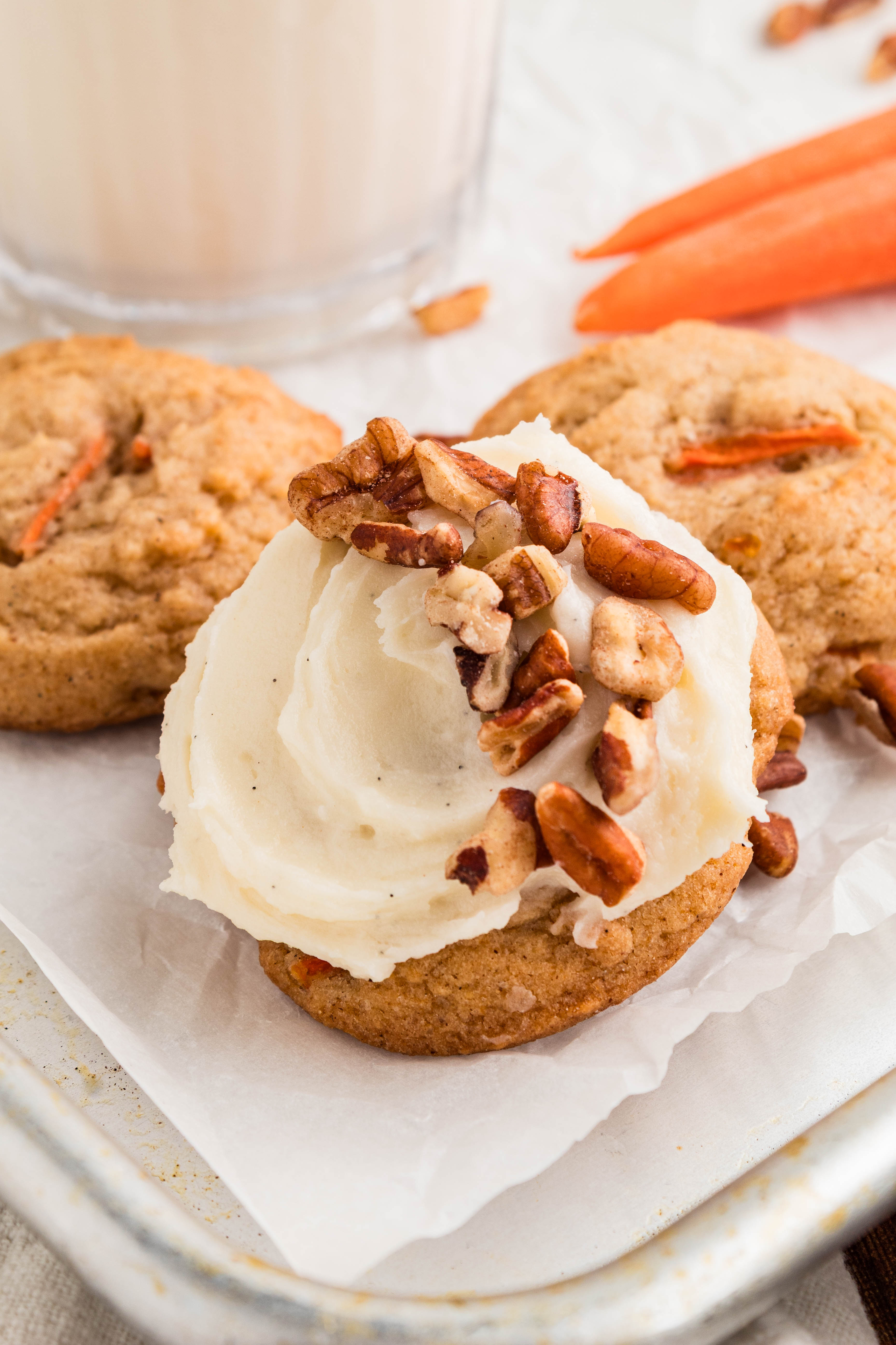 carrot cake cookies with cream cheese frosting and pecans on top