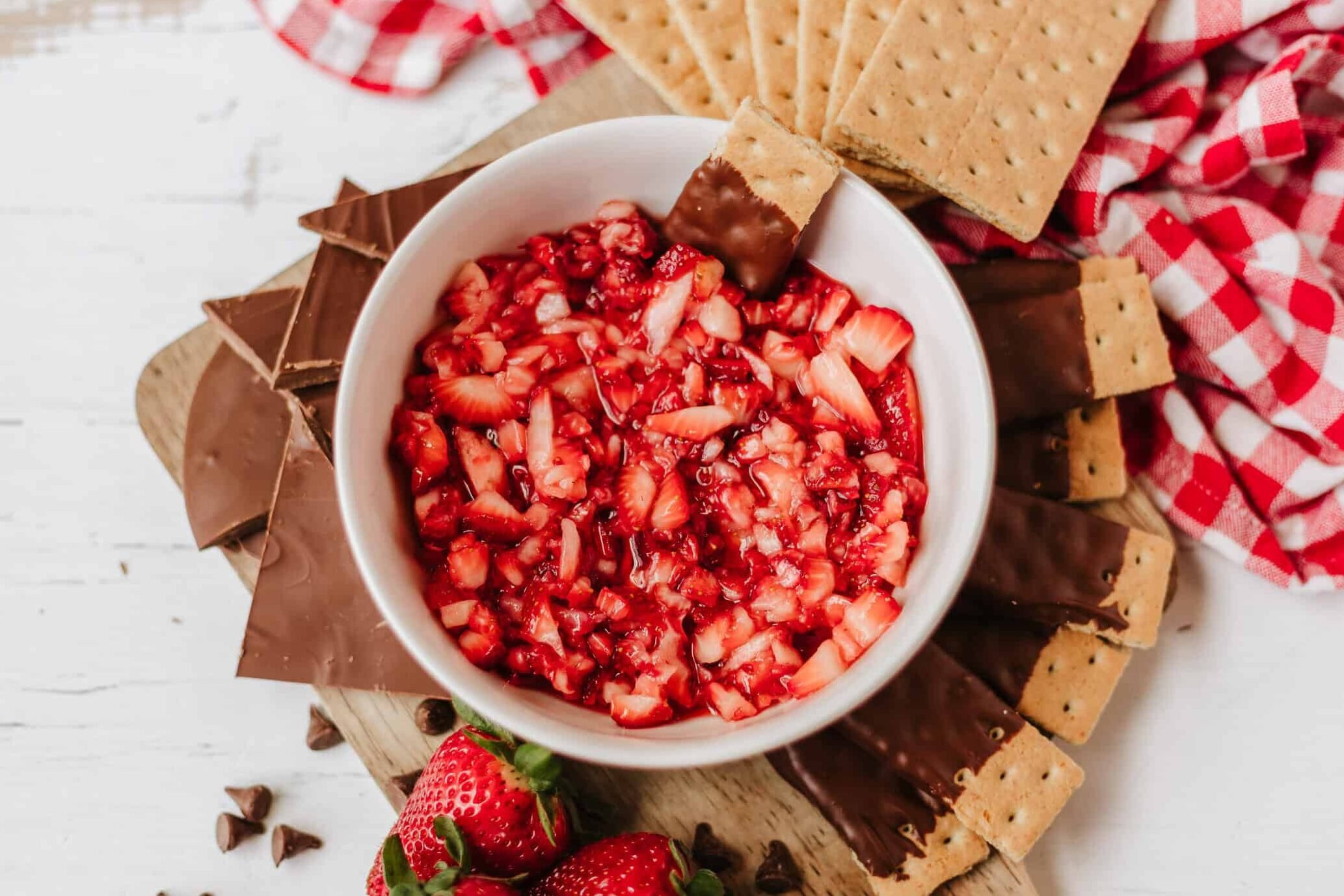 strawberry salsa in a bowl surrounded by chocolate dipped graham crackers on a platter