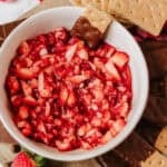 strawberry salsa in a bowl surrounded by chocolate dipped graham crackers on a platter