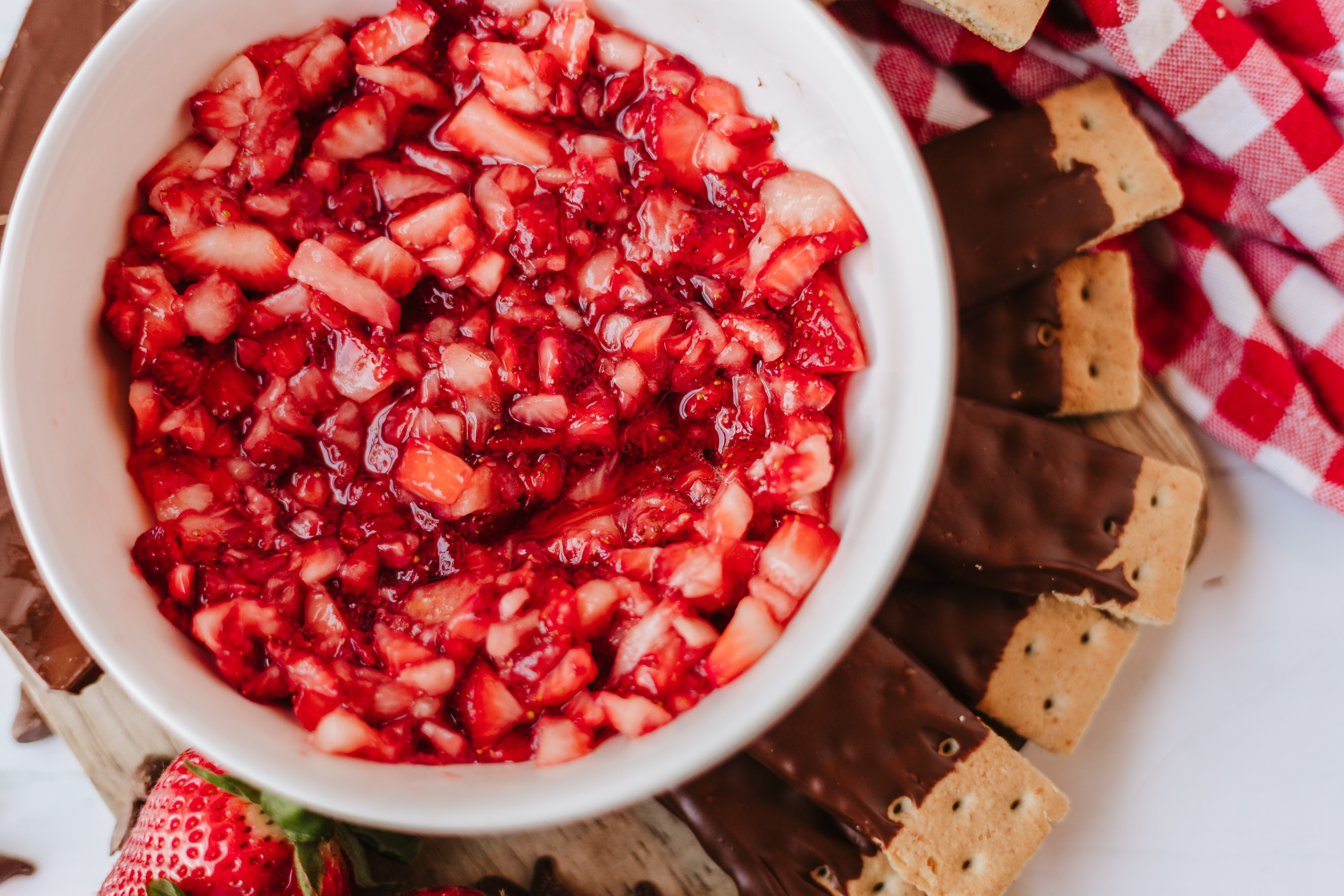 strawberry salsa in a bowl surrounded by chocolate dipped graham crackers on a platter