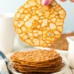lace cookies stacked up and one being held over the stack