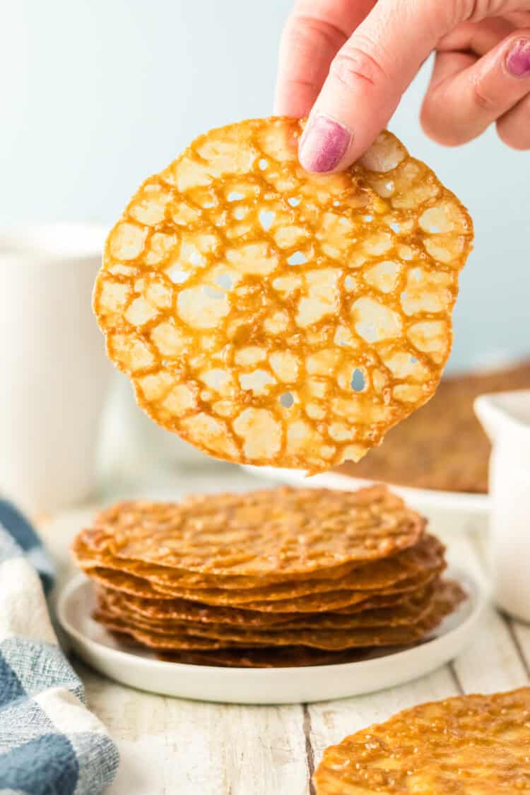 lace cookies stacked up and one being held over the stack