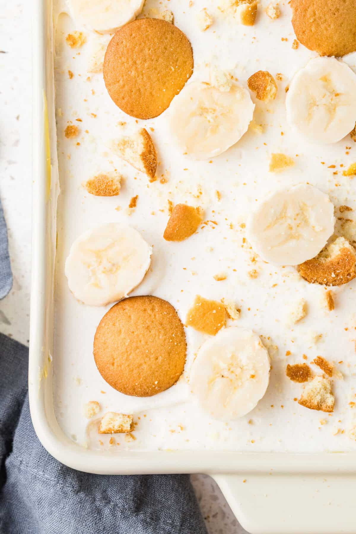the top of a banana pudding poke cake with fresh bananas and vanilla wafers