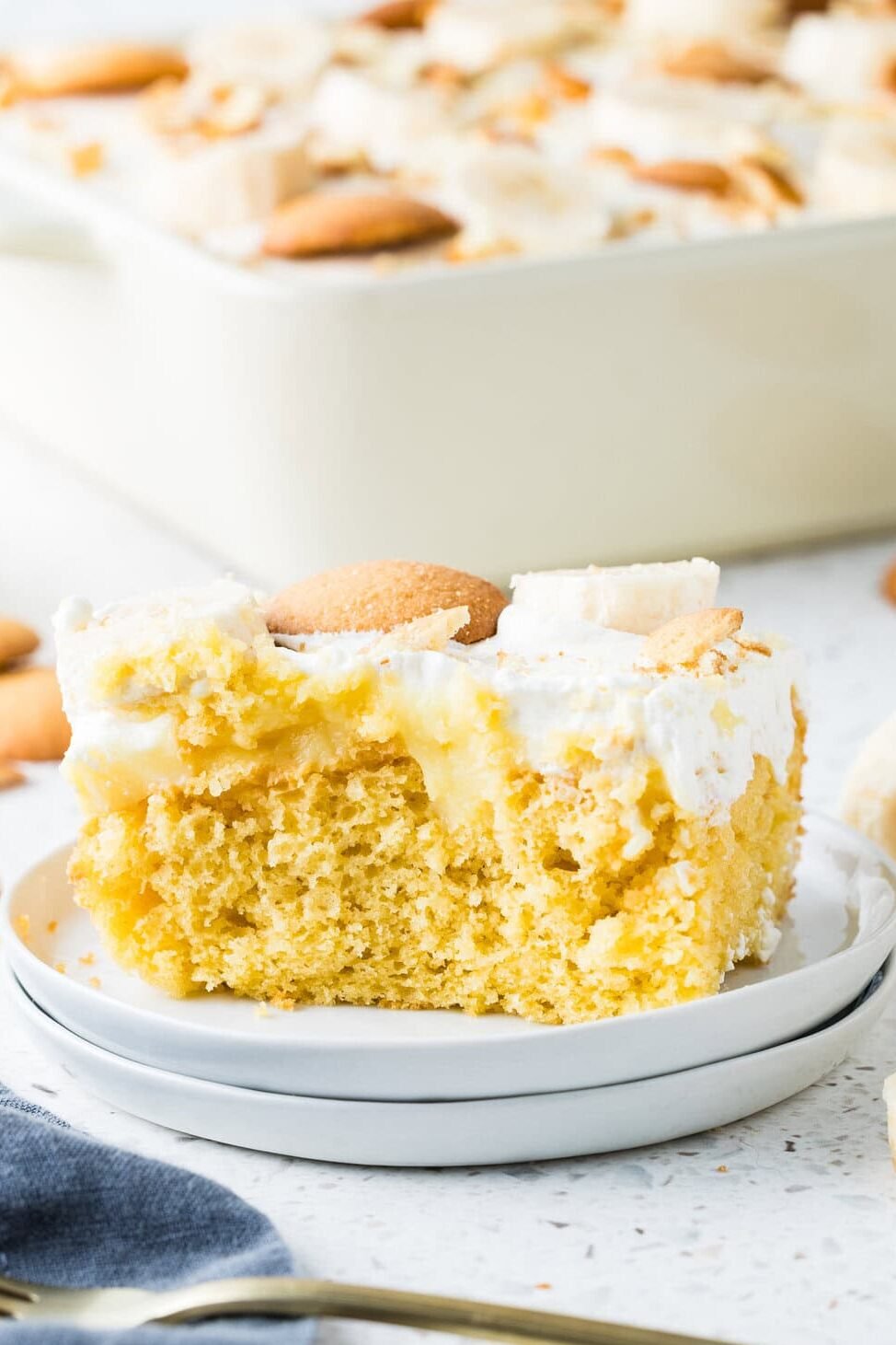 slice of banana pudding poke cake with fresh bananas and vanilla wafers