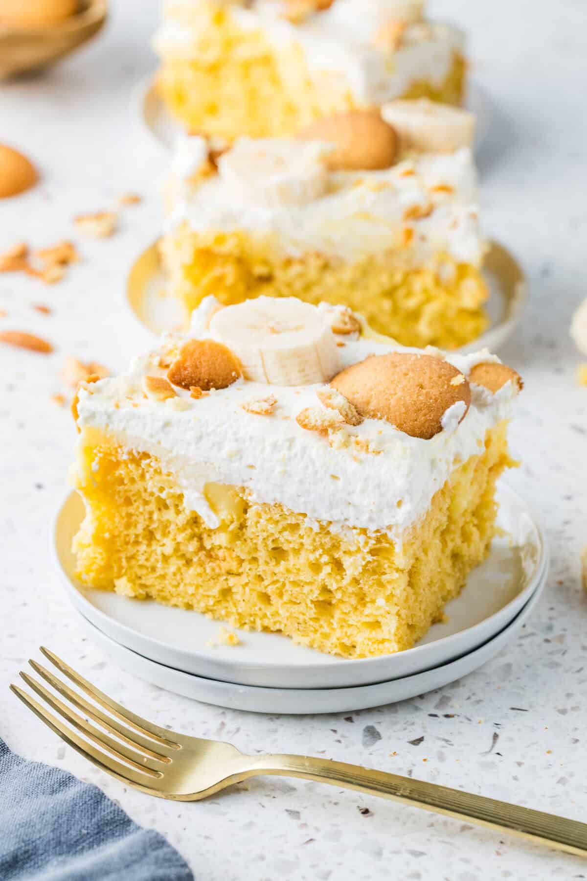 banana pudding poke cake slices on white plates