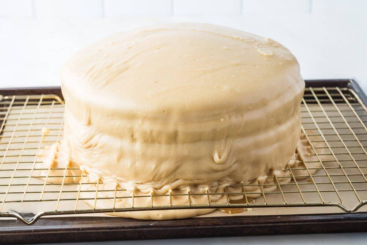 caramel frosting poured over vanilla cake layers with caramel filling
