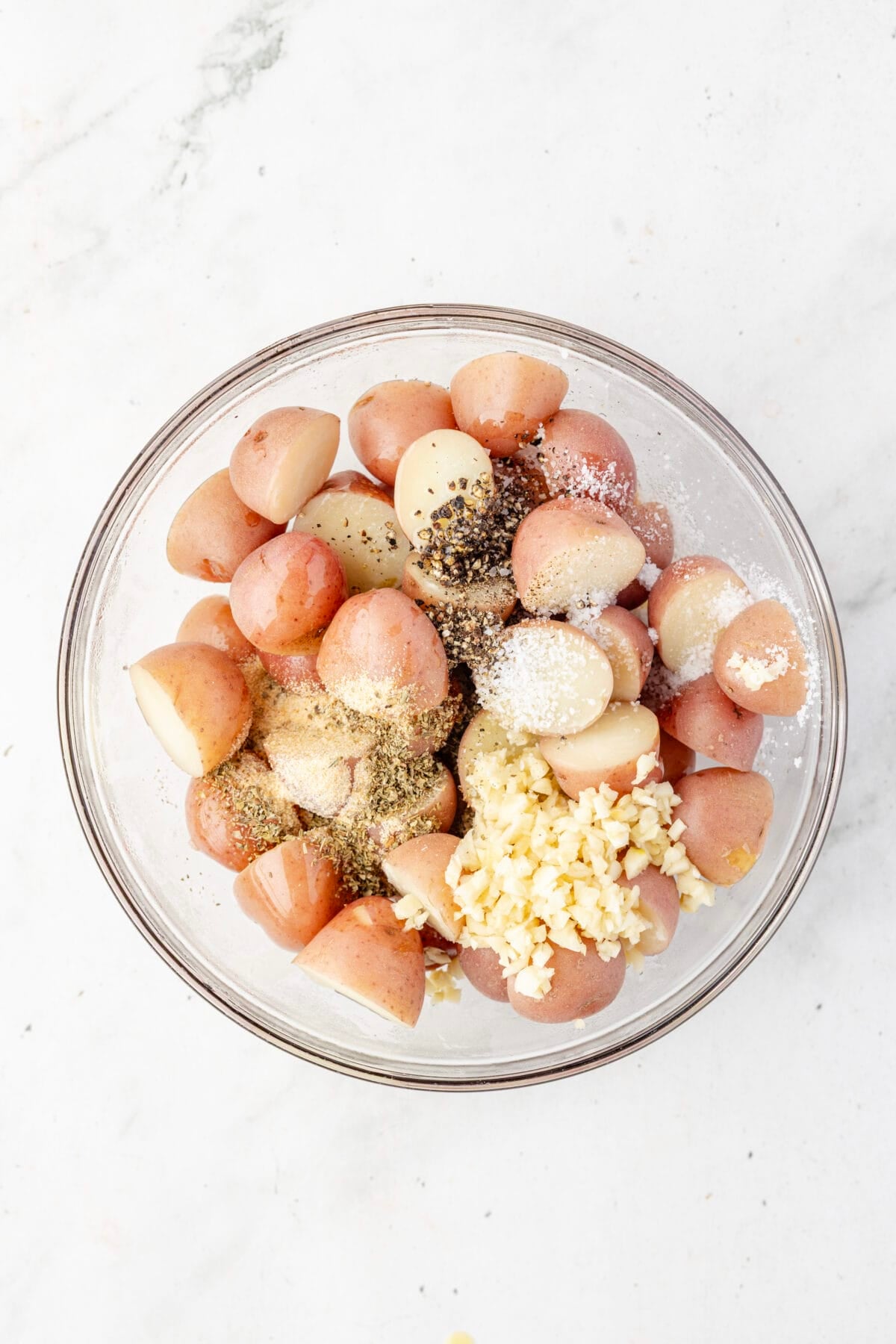 spices and olive oil added to bowl of boiled potatoes