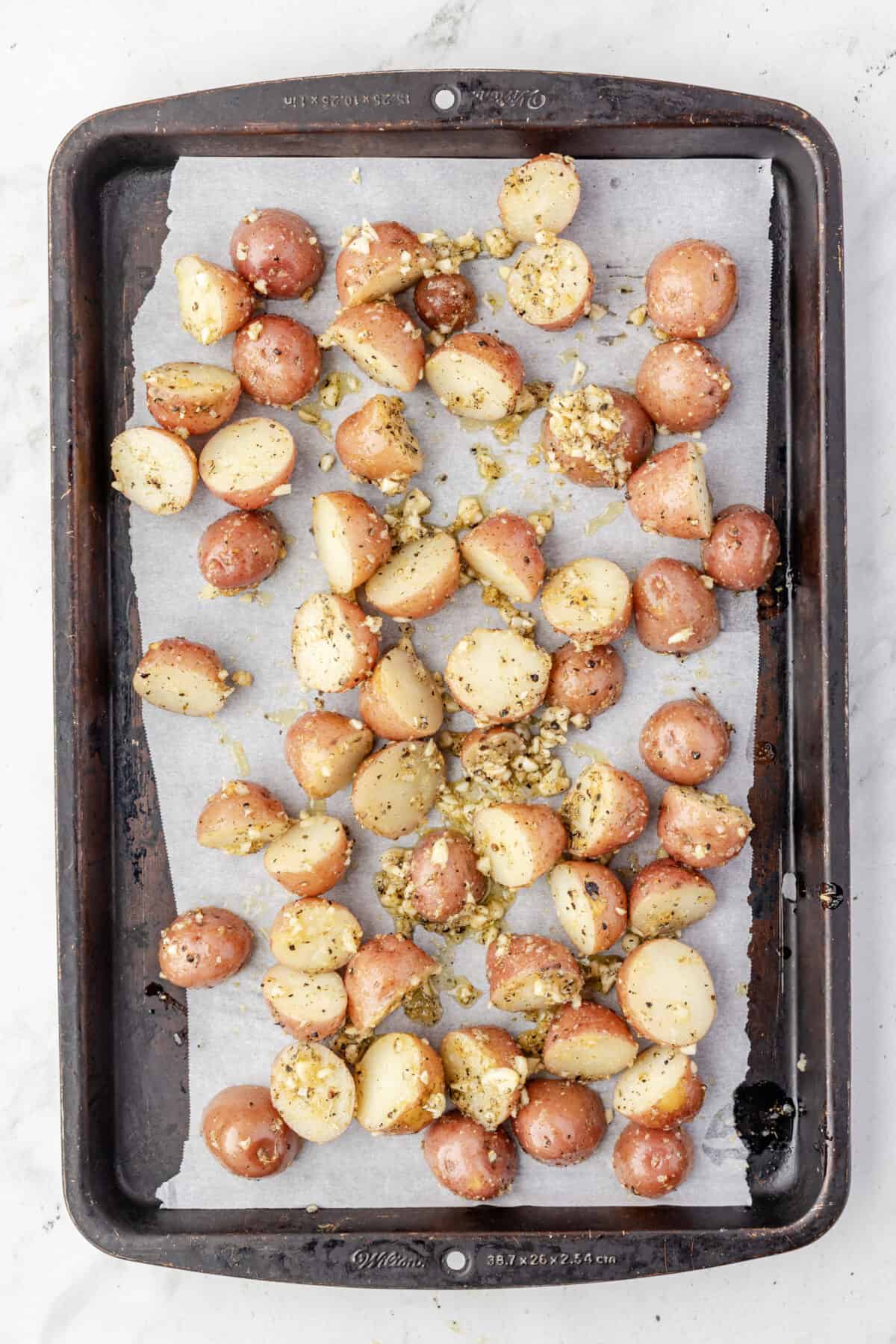 seasoned baby red potatoes spread out on a baking sheet