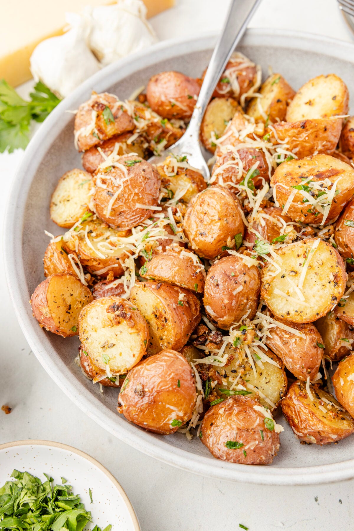 crispy garlic parmesan potatoes in a white bowl