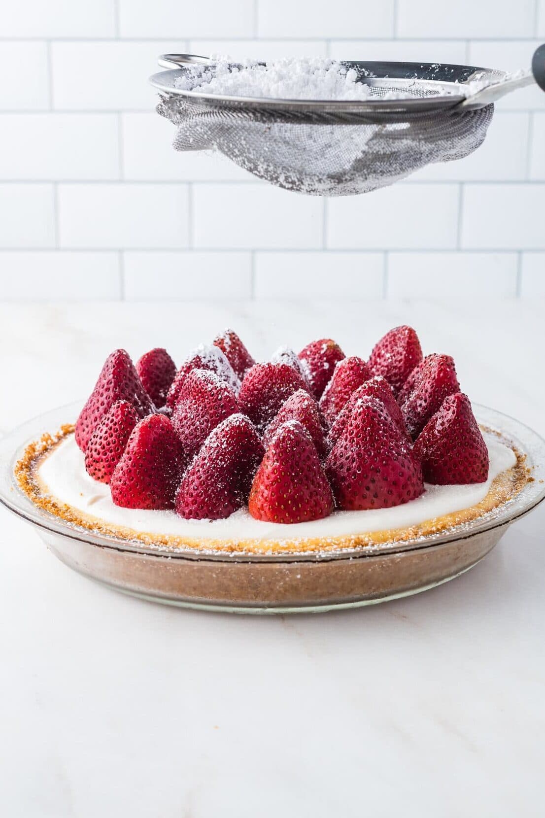 dusting powdered sugar over strawberry cheesecake pie