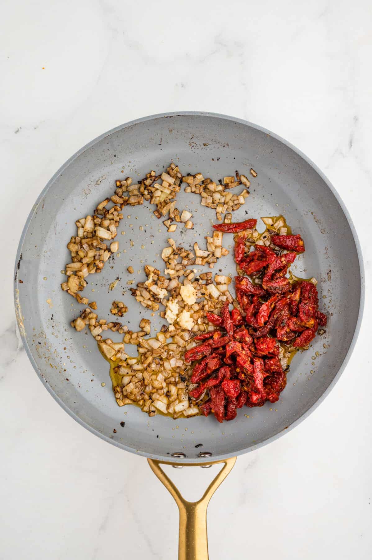 sauteed onion and garlic with sundried tomatoes in a skillet