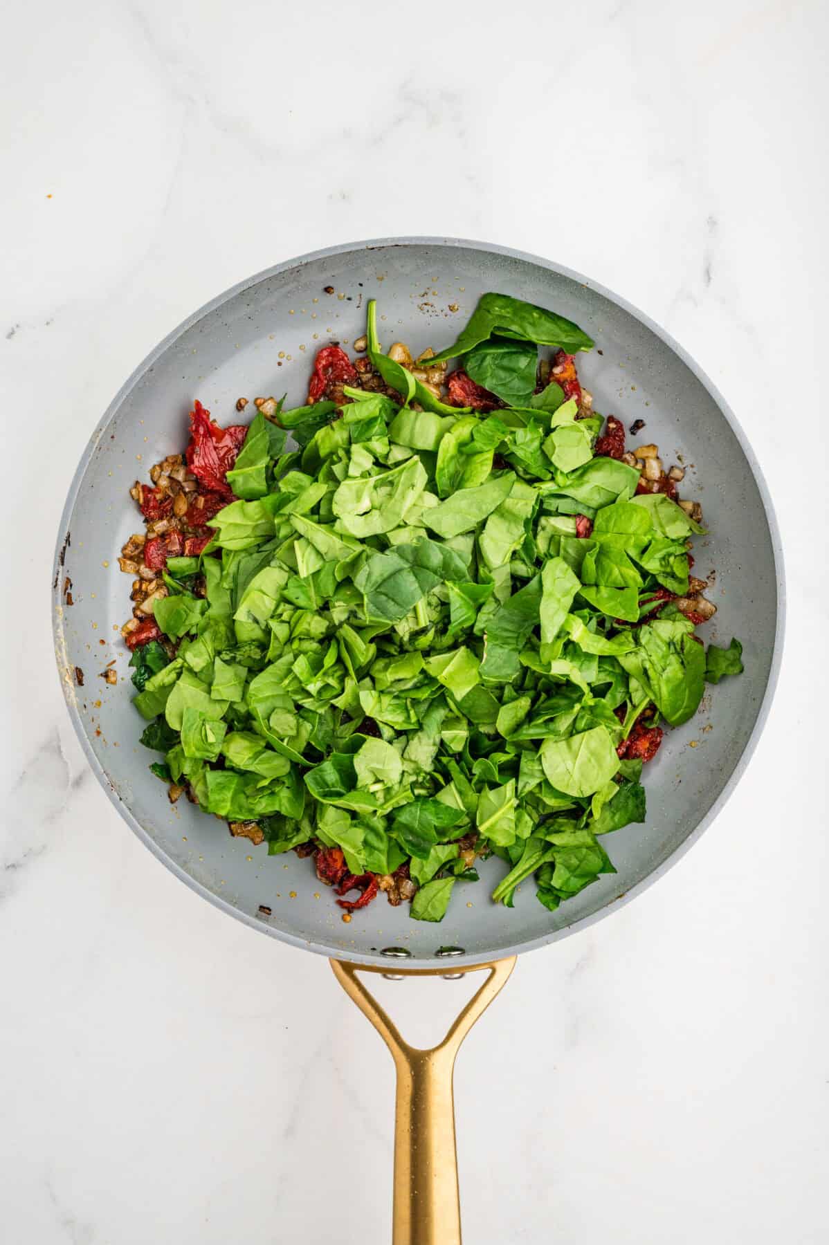 spinached added to sauteed veggies in a skilelt