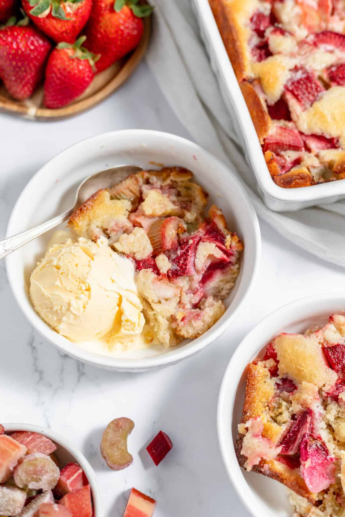 strawberry rhubarb cobbler in a bowl with vanilla ice cream