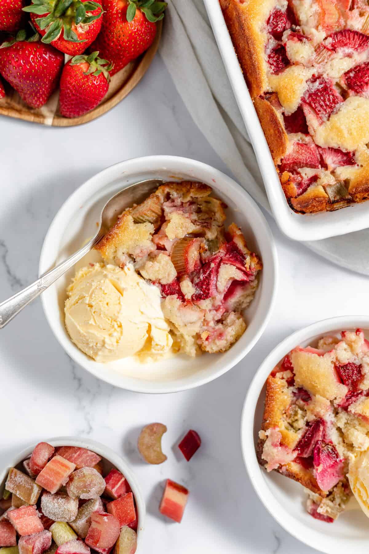 strawberry rhubarb cobbler in a bowl with vanilla ice cream