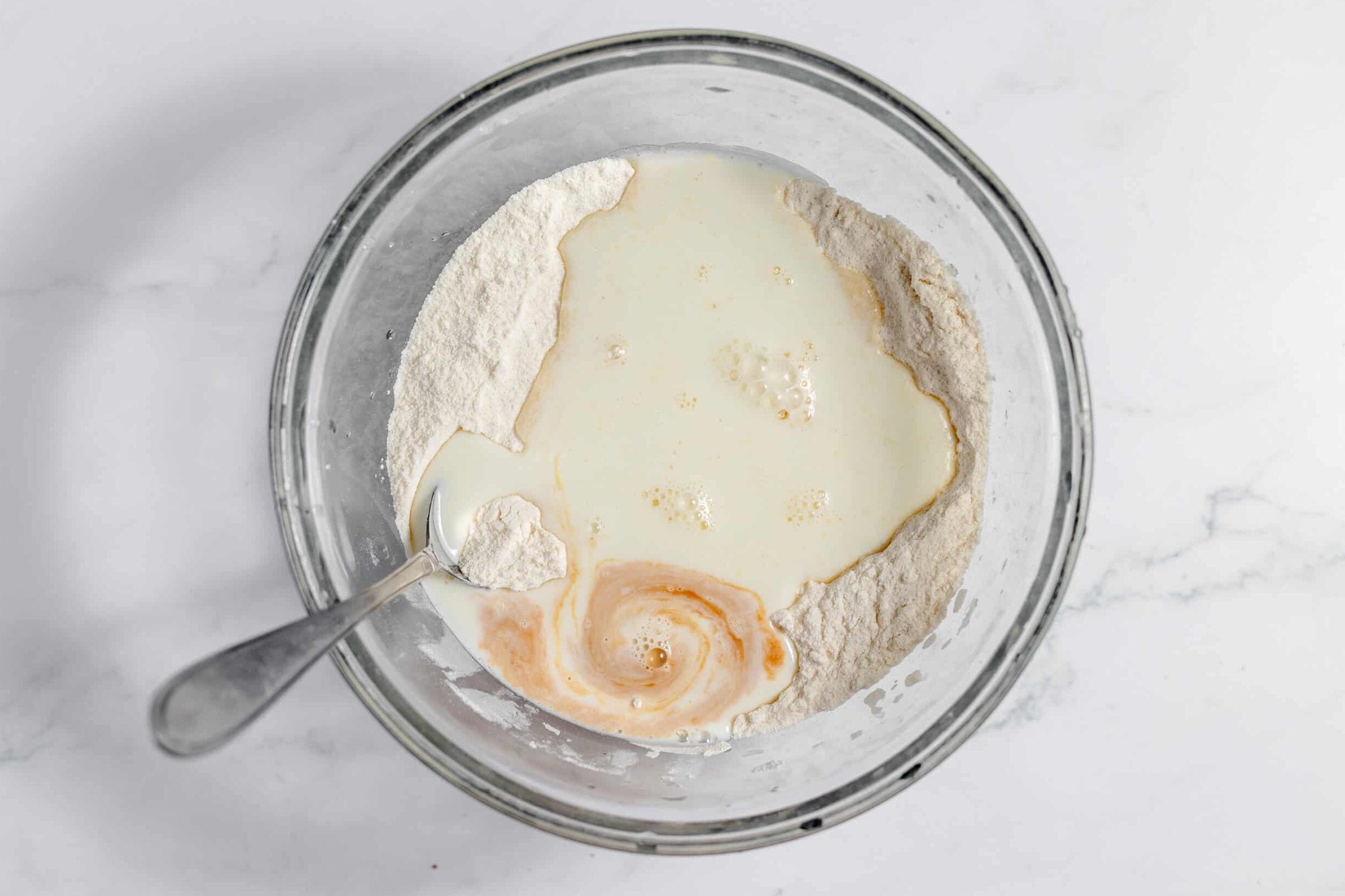 dry ingredients in a bowl with milk and vanilla added