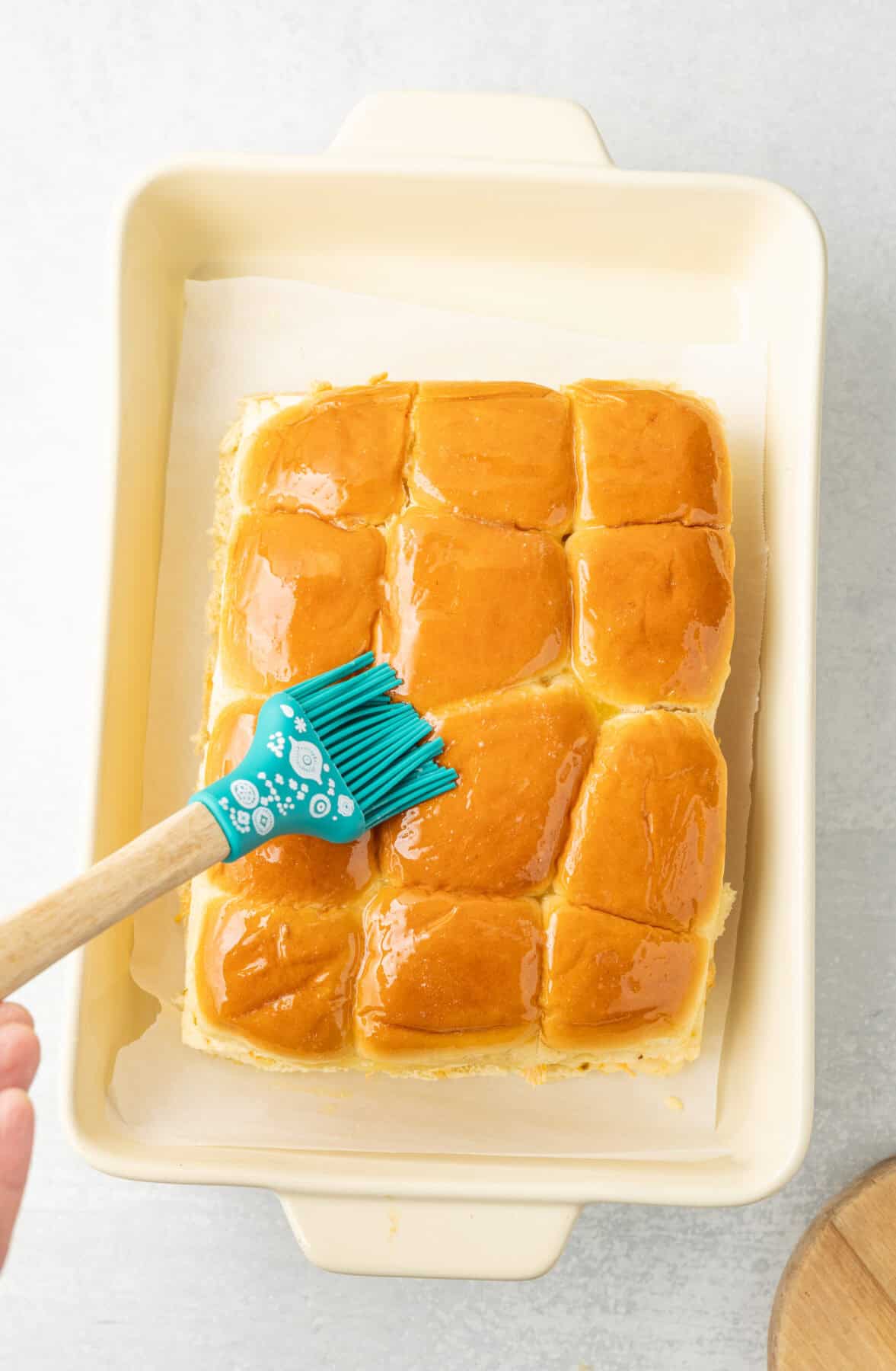 brushing butter on top of the rolls