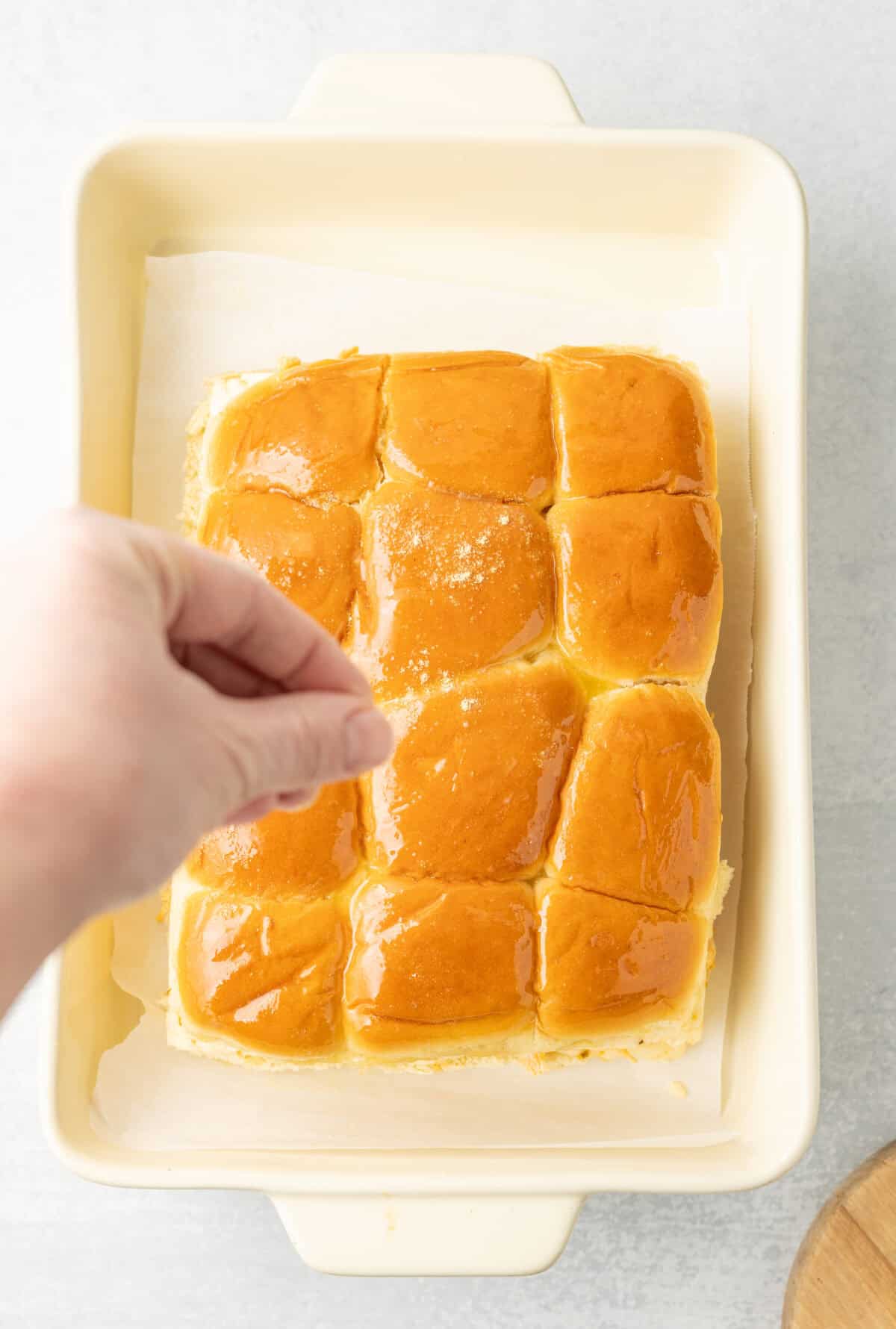 sprinkling spices on top of the buttered hawaiian rolls