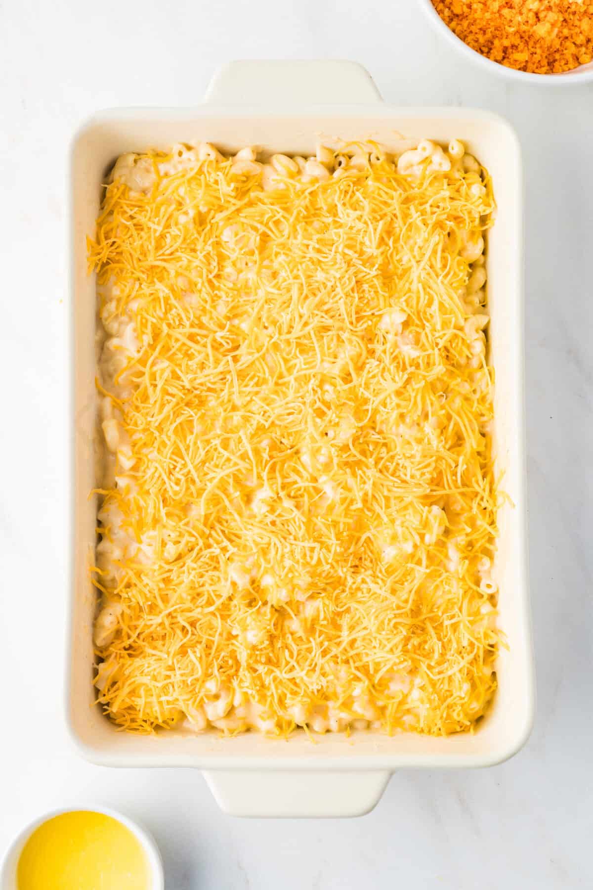shredded cheese on the top of the mac and cheese in a baking dish