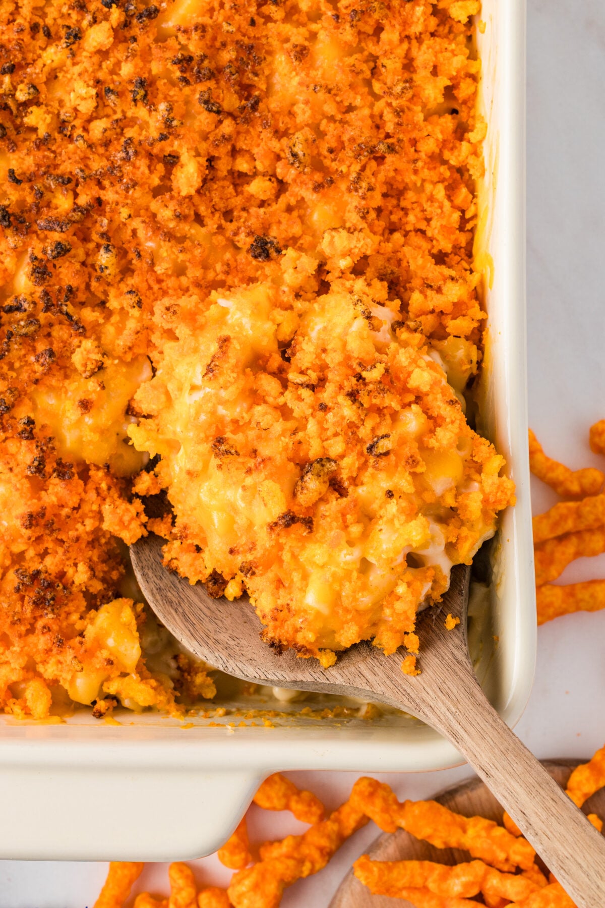 a dish of cheetos mac and cheese with a wooden spoon  in it