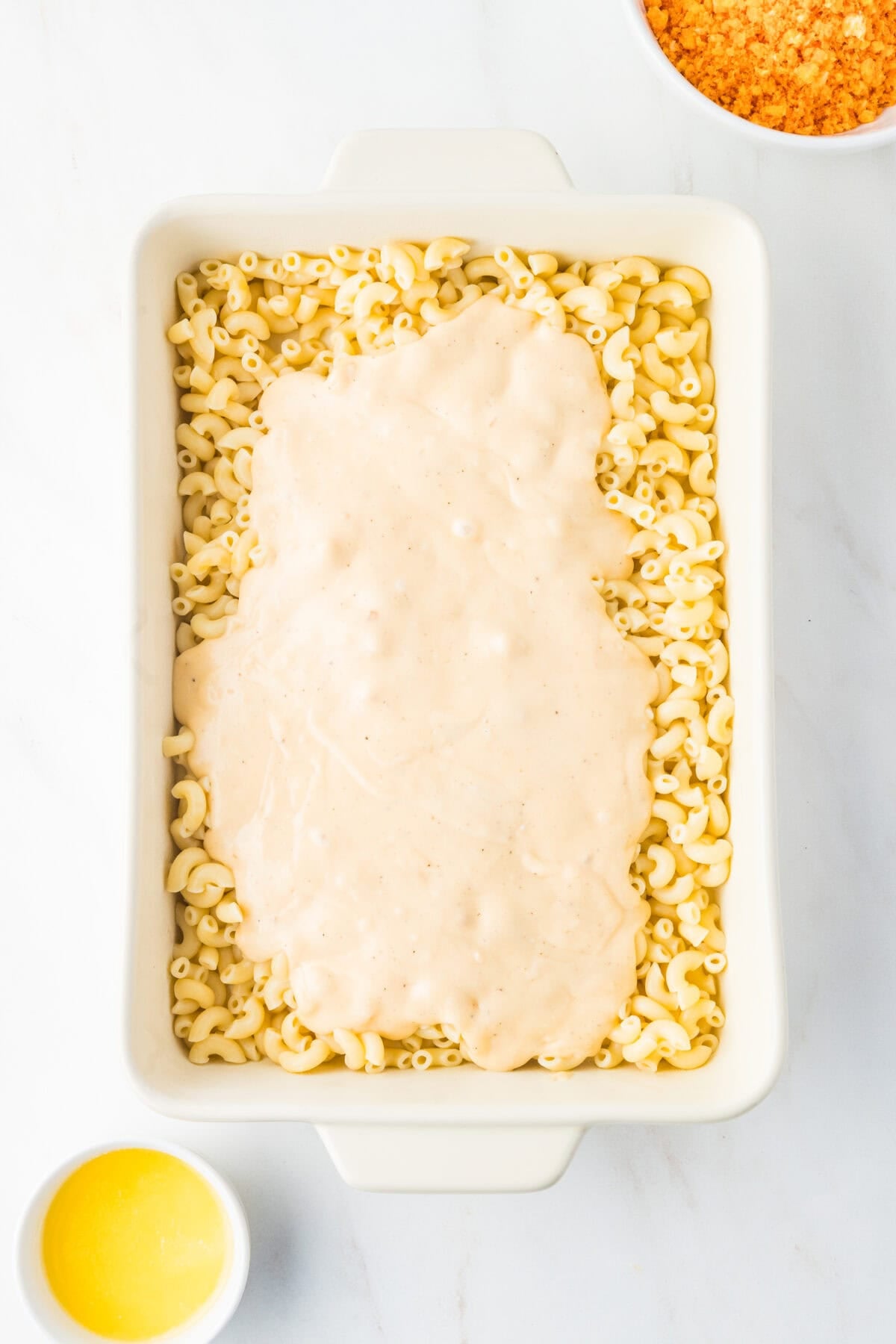 cheese sauce over noodles in a baking dish