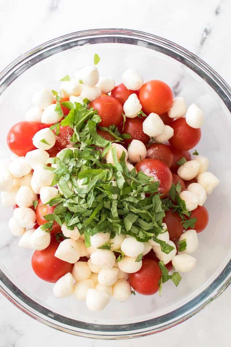 cut up basil added to tomatoes and mozzarella