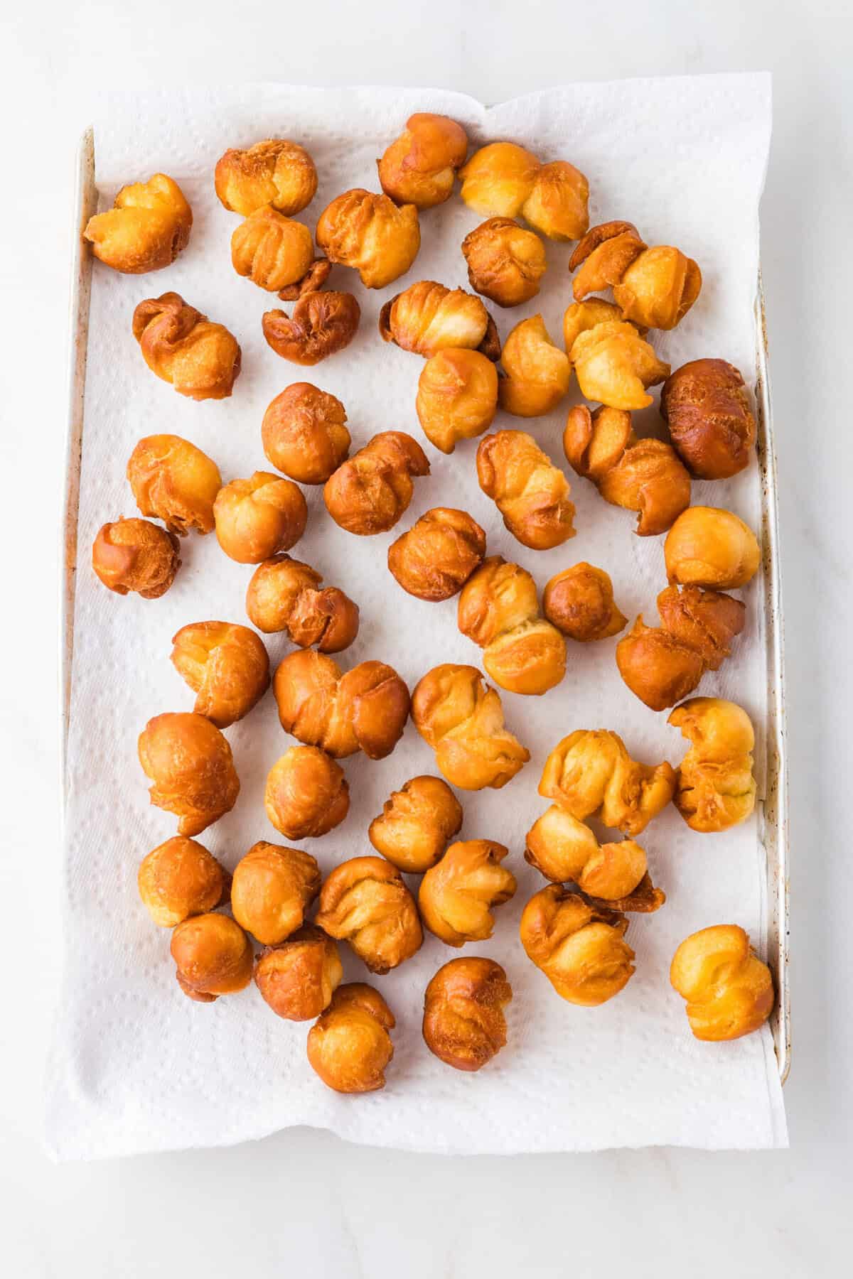 fried biscuit donut holes draining on paper towels