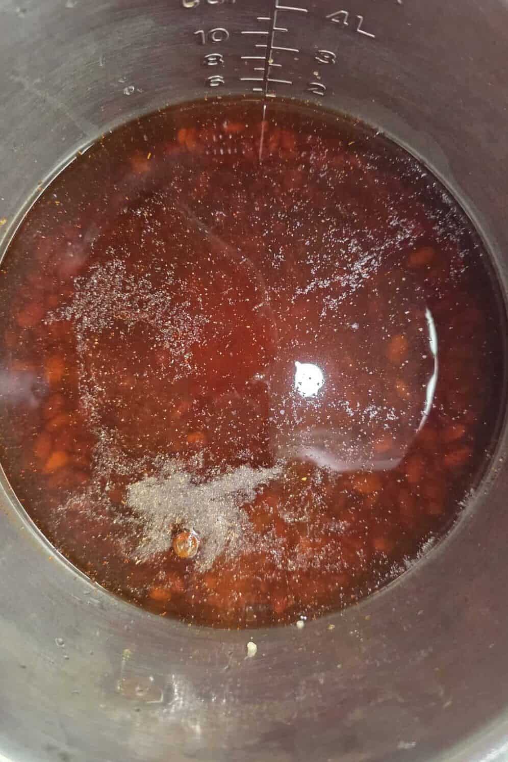 seasonings added to broth and pinto beans in pressure cooker
