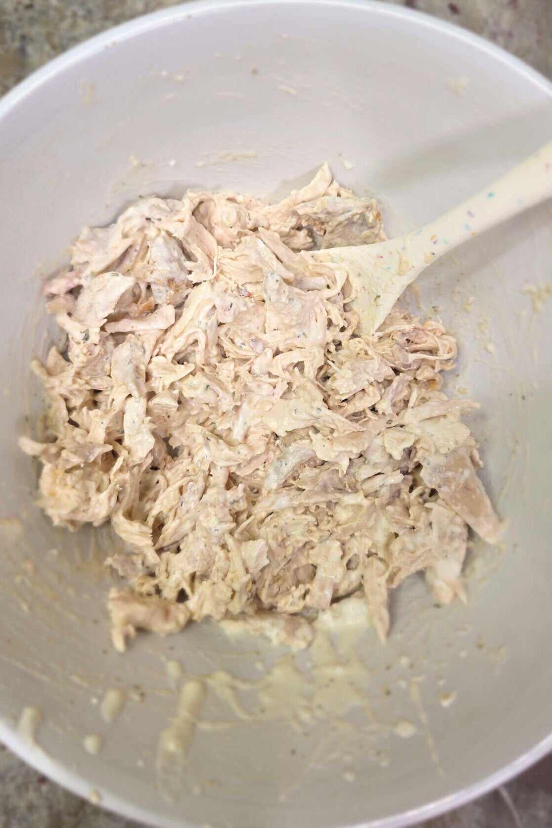 shredded rotisserie chicken in a white bowl coated with ranch and spices