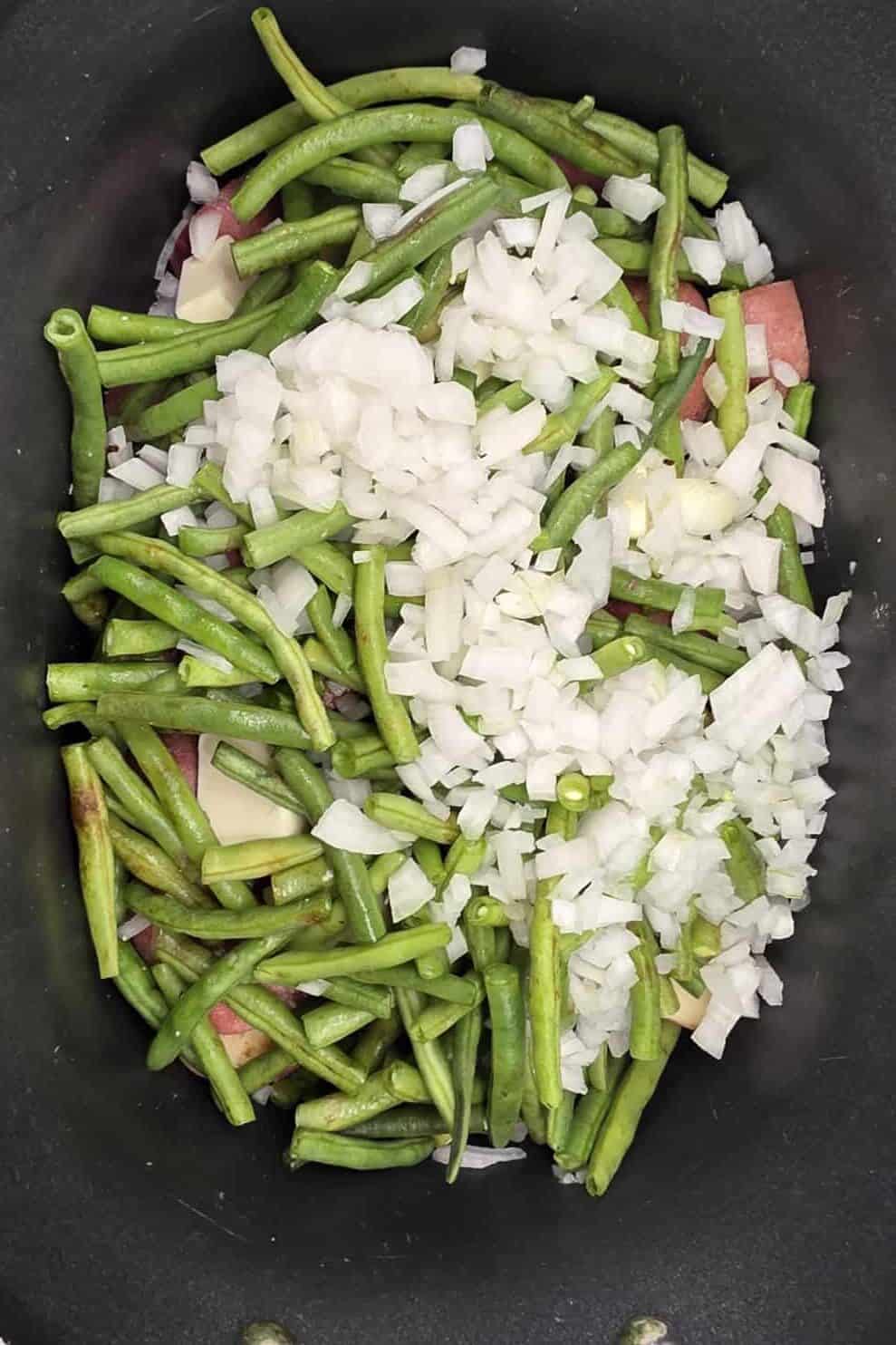 cut green beans and diced onion on top of potatoes