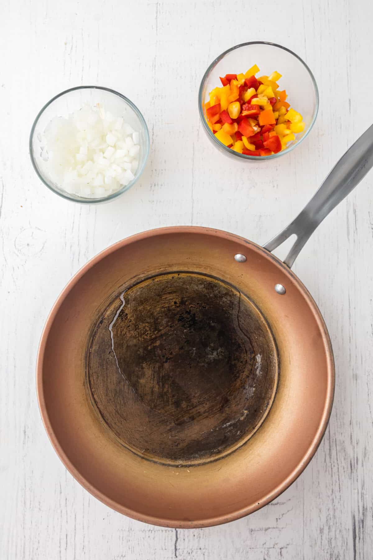 oil in skillet with diced onions and pepper in bowls