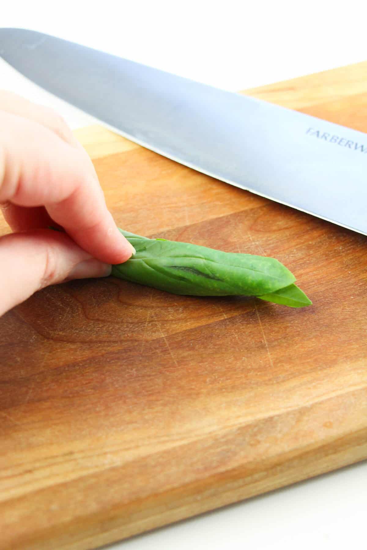 rolled basil leaves on a cutting board
