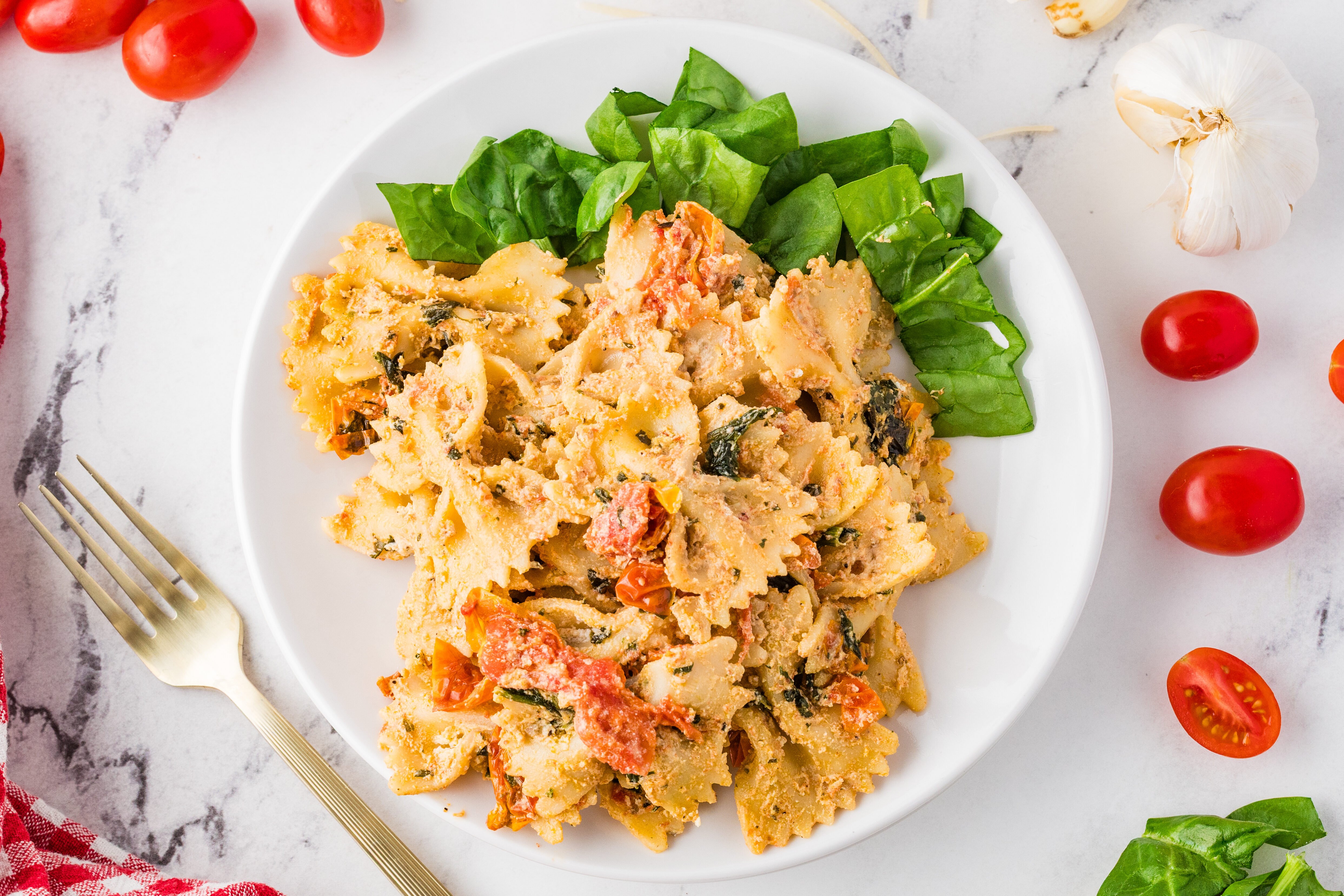 boursin cheese pasta on a white plate with spinach