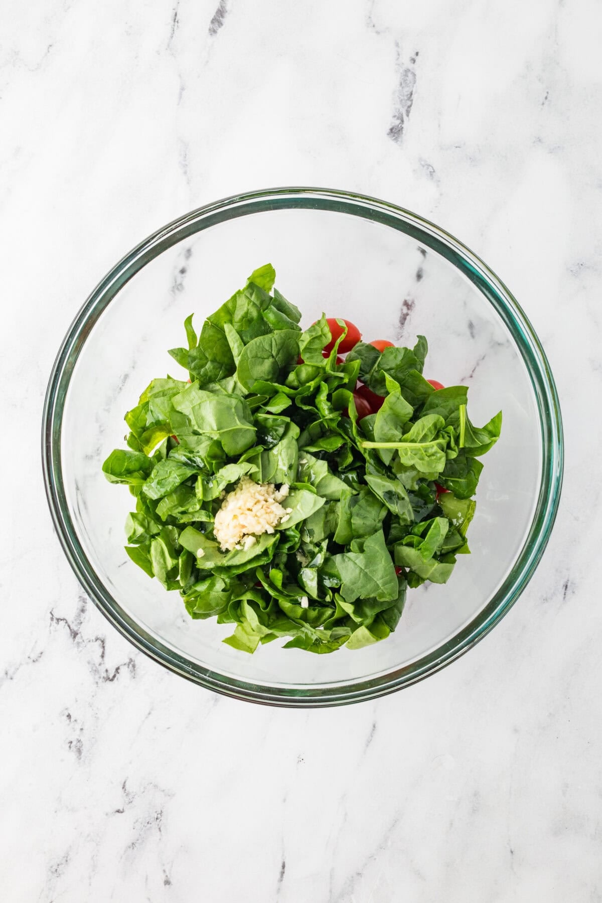 spinach, tomatoes, and garlic in bowl with oil