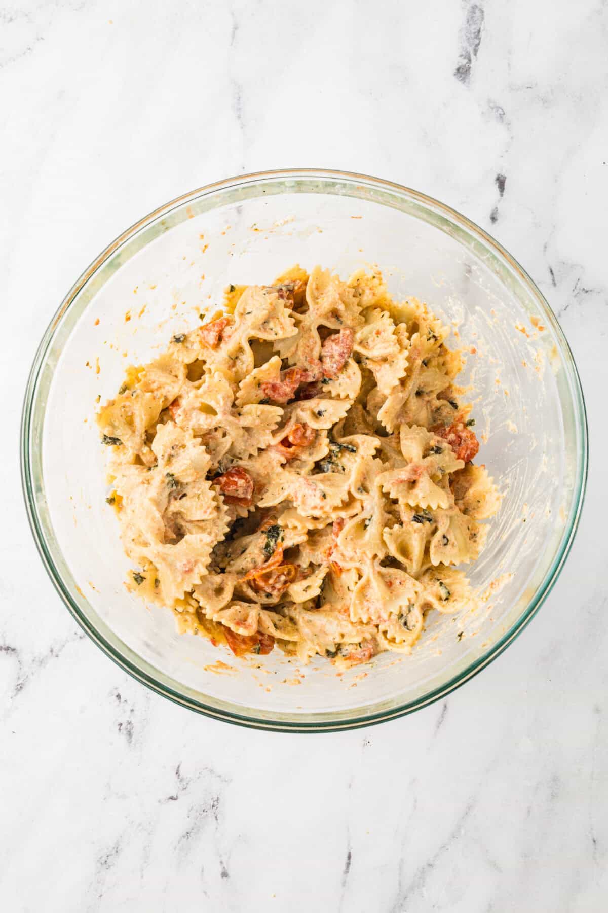 roasted vegetables and cheese added to bowl of pasta and tossed together