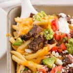 carne asada fries being lifted from baking sheet