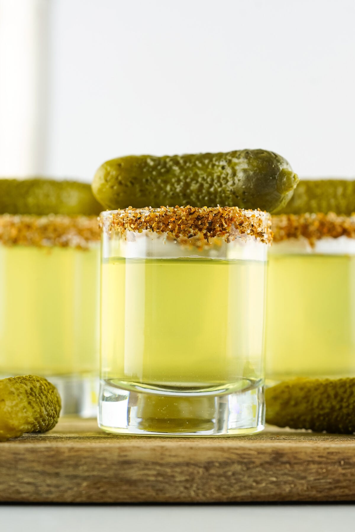 dill pickle shots garnished with tajin and a gherkin pickle